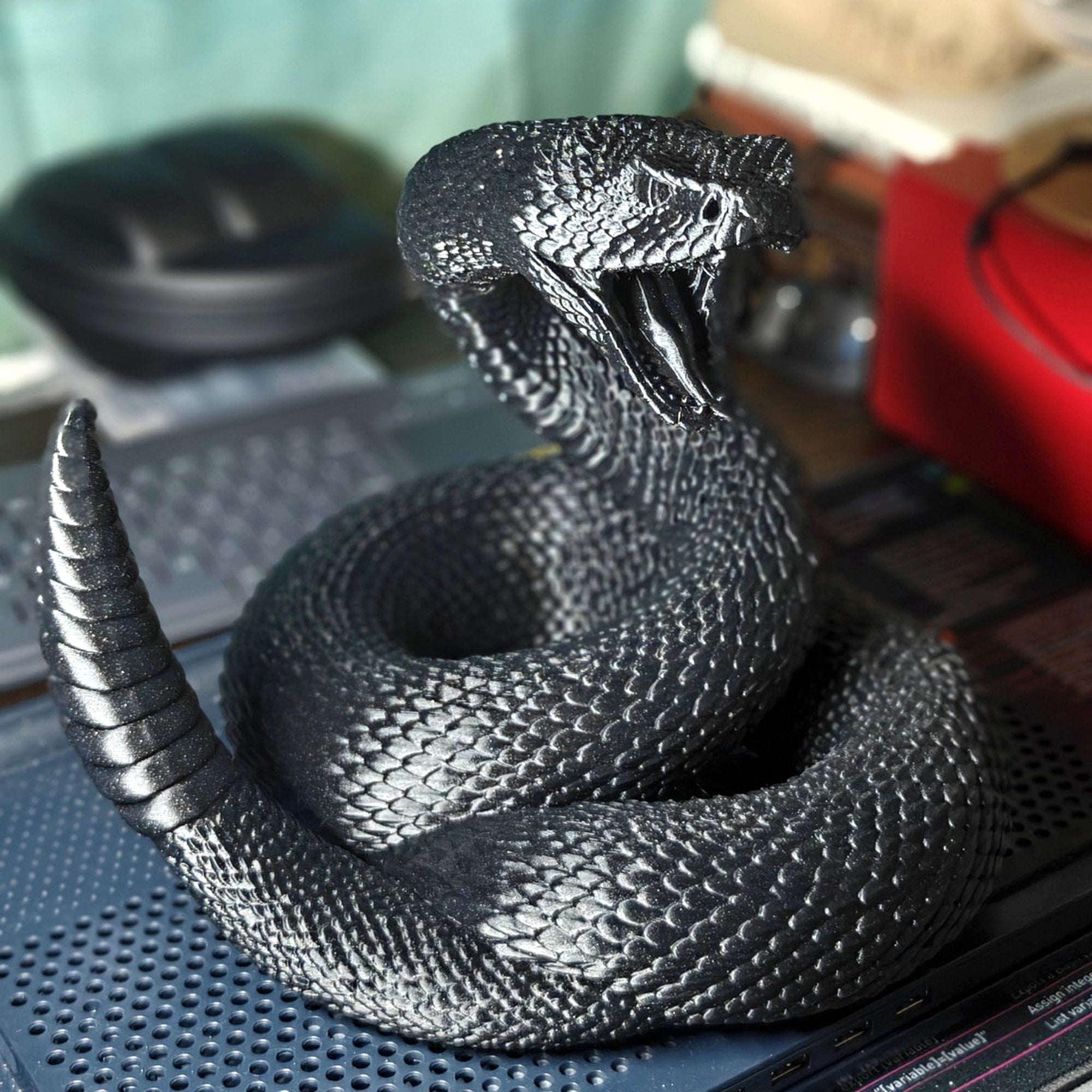 The actual metallic-black rattlesnake print showing its textured scales and layered finish